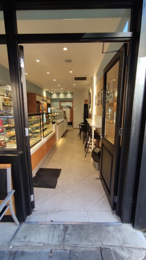 Glass doors with black frames ahead. Push metal handles in centre to open.