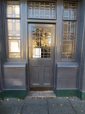 Glass door with black frame ahead. Push from left to open.