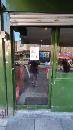 Glass door with green frames. Push green handle on right to push.