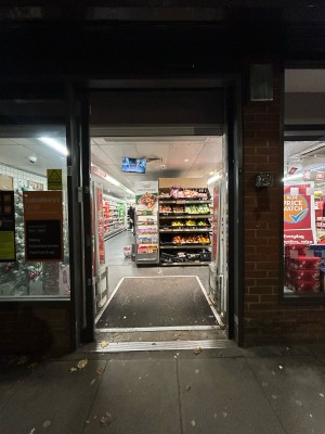 Automatic glass doors with grey frame. Detectors beyond on left and right.