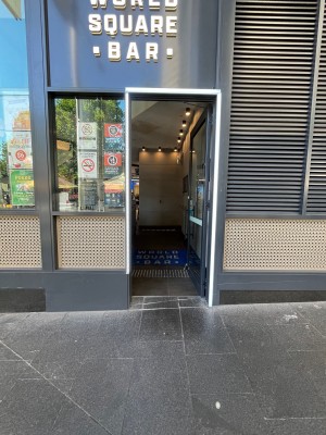 Glass door with grey metal frame. Push from left.