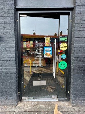 Glass door with black frame. Push metal handle on right to open.