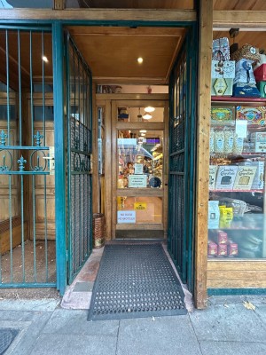 Preceding green iron gates, push from middle to open. Glass door with wooden frame following, push from right to open.