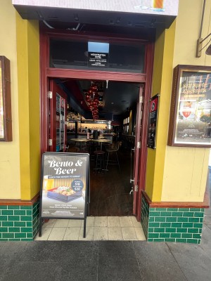 Glass double doors with dark red wooden frame. Push from middle. A-frame sign obstructing on left.