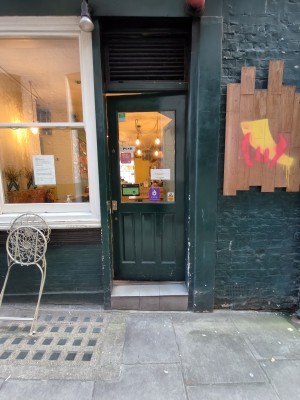 From back street facing green glass panelled door. Push golden metal handle on left to open.