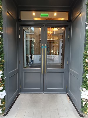 Power assisted glass doors with grey frame ahead. Pull golden, metal handle in middle to open.