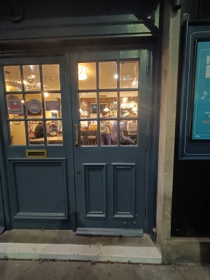 Glass door with blue frame. Pull golden, metal handle on left to open.