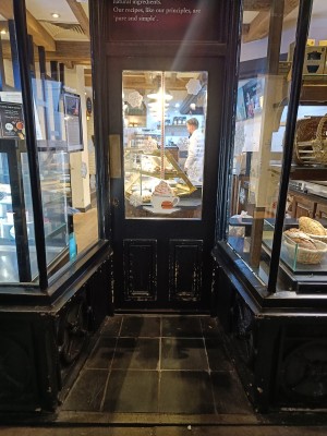 Glass door with black frame. Push on left to open.