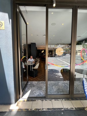 Glass double doors with brown metal frame. Turn handle and push left door from middle to open.