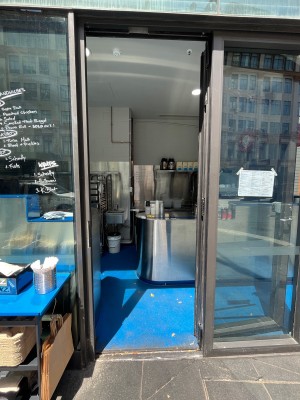 Glass door with grey metal frame. Push from right.