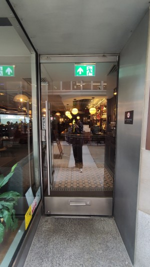 Glass door ahead. Pull metal handle on left to open. Glass wall along left.