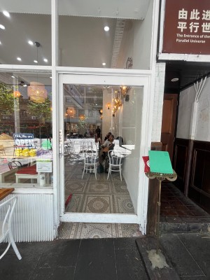 Glass door with white wooden frame. Turn silver handle and push from left.