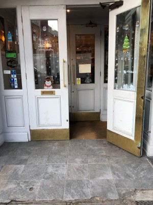 White wood and glass doors. Pull from gold metal handle in centre to open.