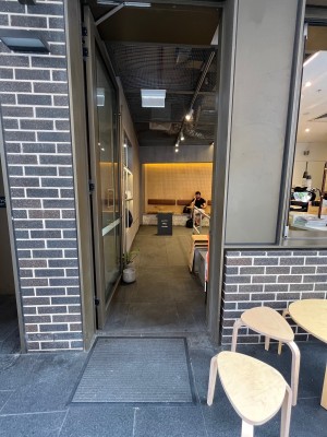 Glass door with grey metal frame. Push from right. Doorstop obstructing on left when door kept open.
