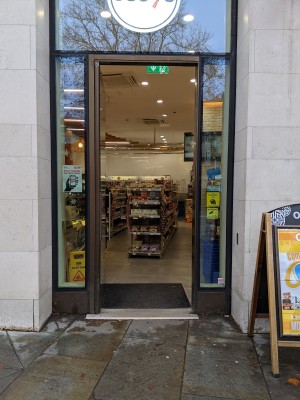 Glass door with black frame. Metal handle on right. Push to open.