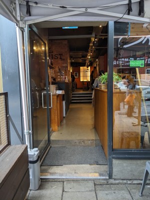 Glass door with black frame. Metal handle on right. Push to open.