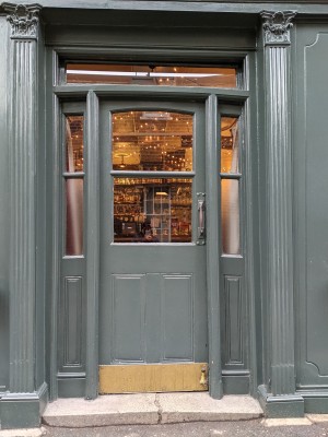 Green wood paneled glass door. Push from metal handle on right to open.