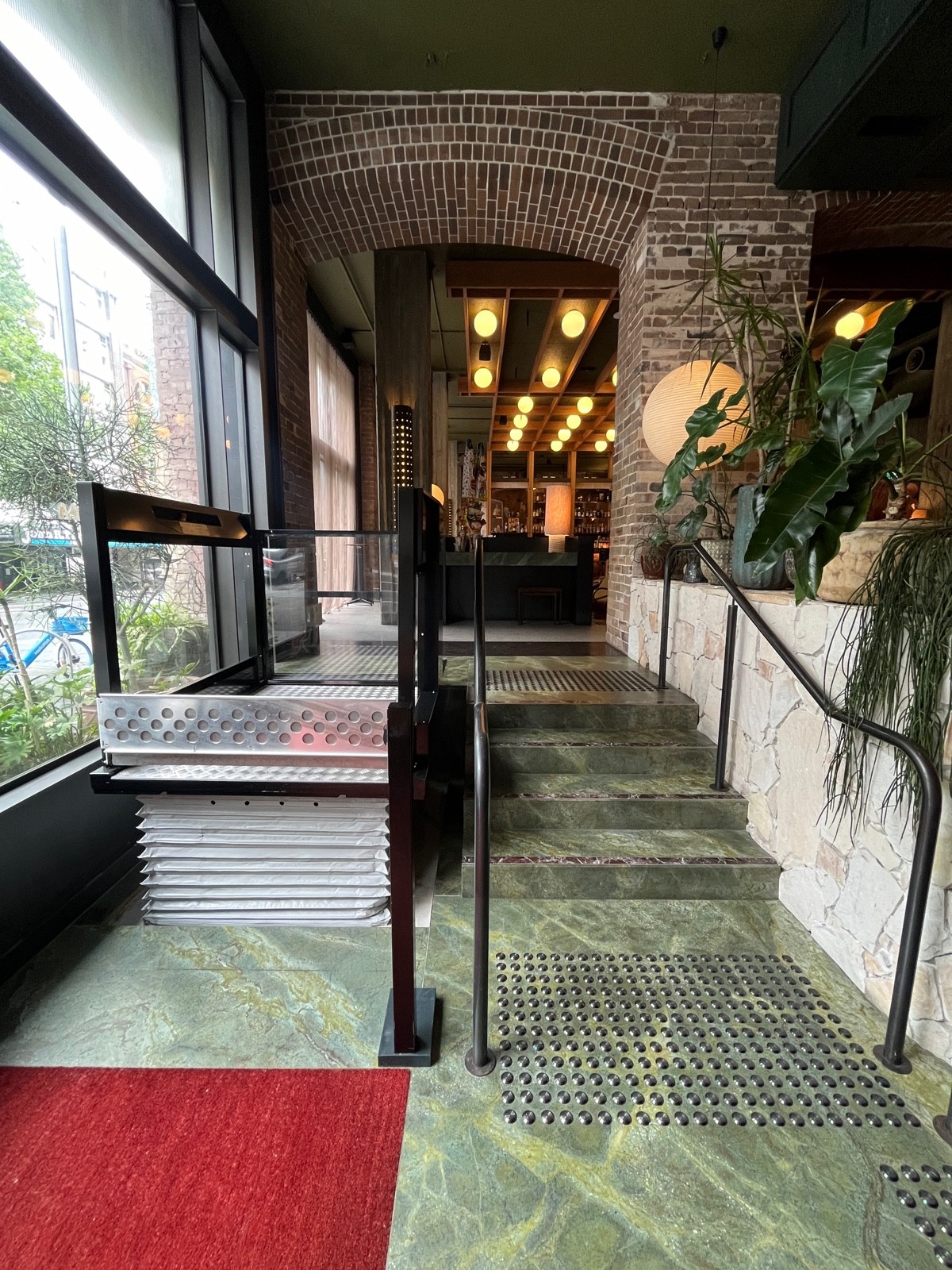 From entrance facing left. Platform lift to left ahead, steps to right. 4 steps up to floor, handrails either side, tactile flooring both