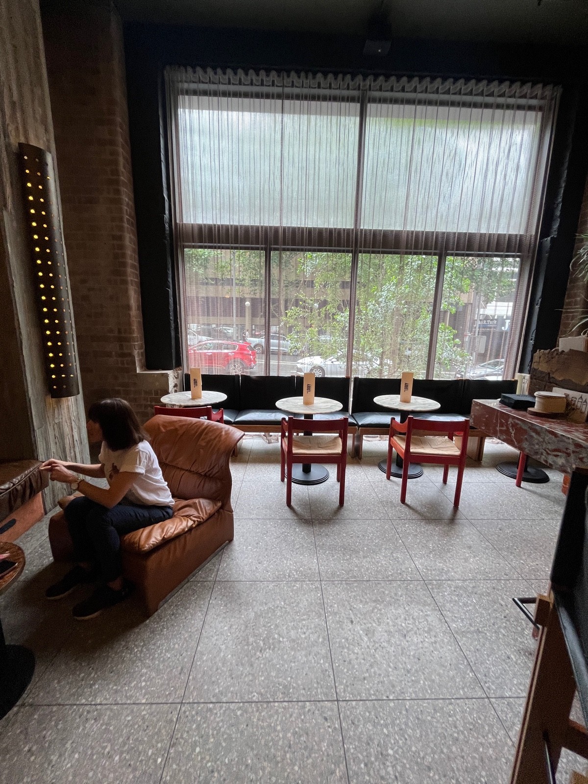 From after armchairs facing straight. Half booth with low table and armchairs on left wall. Half booths directly ahead. Bar on right.