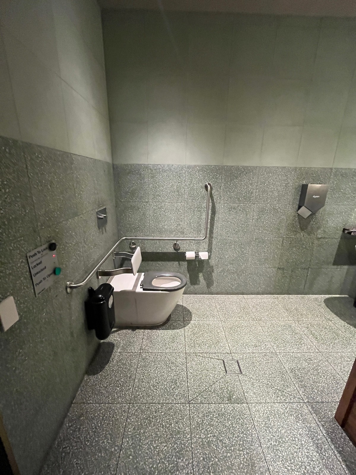 From door facing left. Buttons to lock and open door on left wall followed by toilet.