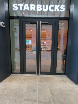 Facing black framed glass doors. Push silver metal handles in centre to open.
