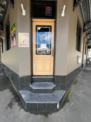 Beige wooden door with glass panel. Three steps up to door. Push from right.