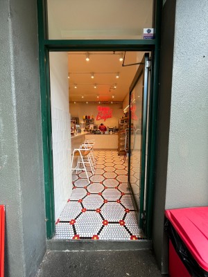 Glass door with green metal frame. Push from left.