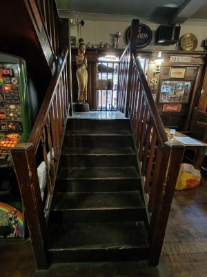 From right end of main area of Crown and Cushion facing right. Stairs going up to landing. Wooden handrails on both sides.