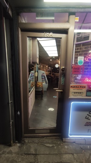 From pavement facing venue. Glass door with grey frames. Push metal handle on right to open.