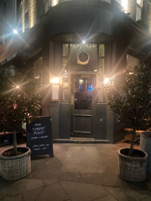 From side street, facing venue. Path ahead to entrance door on back. Planters on both sides. Push door to open via metal pad on left.