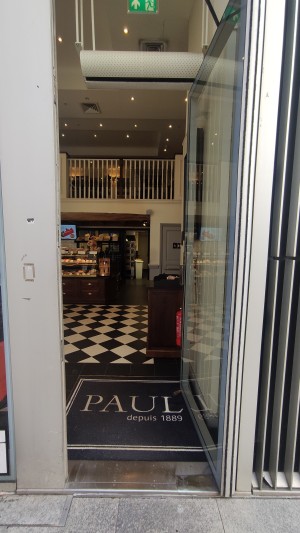 Glass door with grey frames. Push on left to open.