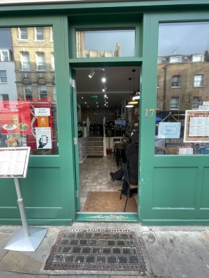 Glass door in green frame. Push on right to open. Seating to immediate right after door, veering into path when occupied.