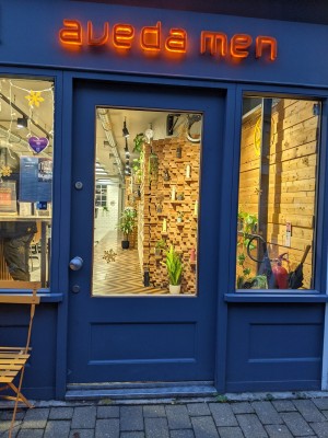 From pavement facing venue. Glass and wood door with metal handle. Push from left to open.