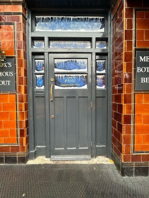 Grey wooden door with glass panels ahead. Pull gold handle on left to open.