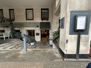 From pavement facing venue. Stairs ahead. Pillar to right with doorbell.