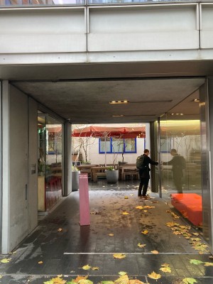 From side street, facing venue. Opening ahead. Standing sign behind.