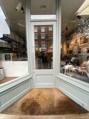 Glass door, with grey wooden doorframe. Handle on left. Pull to open.