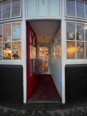 Red framed preceding glass door with white border. Metal push to open handle on right.