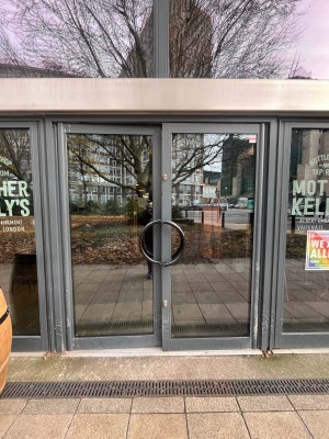 Glass doors with grey metal frame. Push from middle.