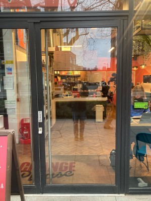 Glass door with black frame. Push to open from left.
