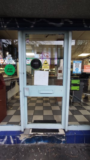 Glass doors with blue frames ahead. Push handle on left to open.
