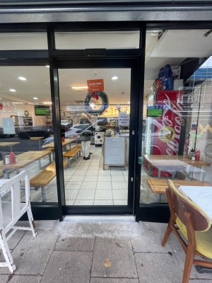 Glass door with black frame ahead. Push button to right of door to slide open from right to left.