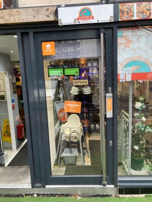 Glass door with black frame ahead. Push door to open via handrail on right.