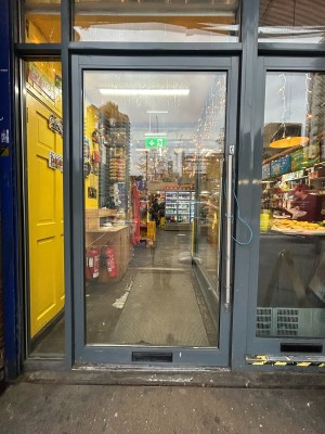 Glass door with grey frame ahead. Pull silver handle on right to open.