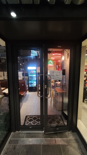Glass doors with black frames. Pull metal handles in centre to open.