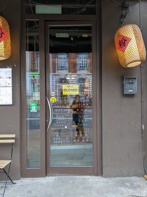 Glass door with brown frame and metal handle. Push left to open.