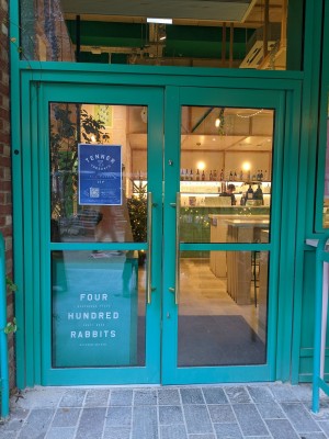 Glass door with green frame and metal handles in centre. Pull to open.