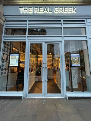 From sidewalk facing venue. Glass double doors white frames. Push to open metal handles in center.