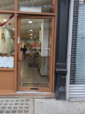 Glass door with brown frames. Push brown handle on left to open.