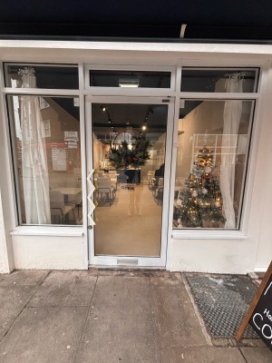 Glass door with white door frame ahead. Push white handle at left to open.